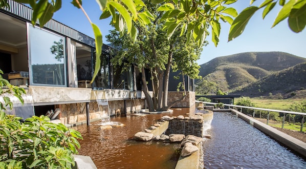Un edificio moderno con una fuente de agua y vistas de las colinas circundantes.