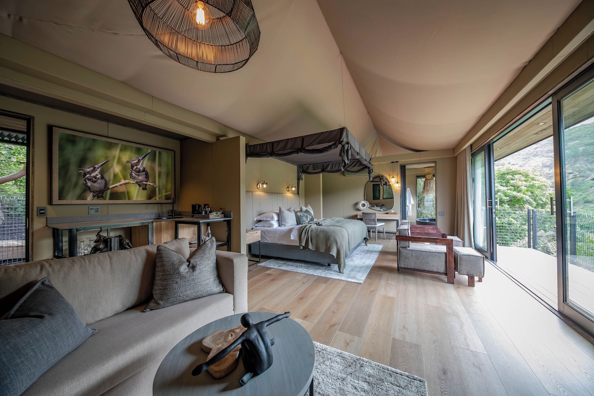 Un dormitorio moderno con una cama grande, un sofá, una mesa de comedor y vistas al exterior.