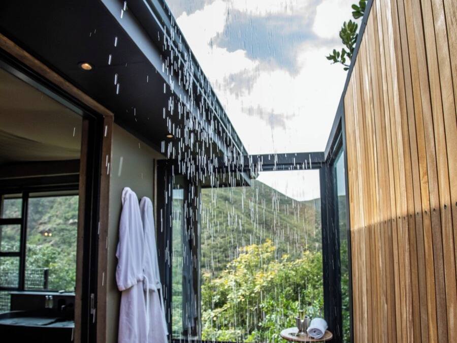 A wooden deck with a glass wall overlooking a lush garden.