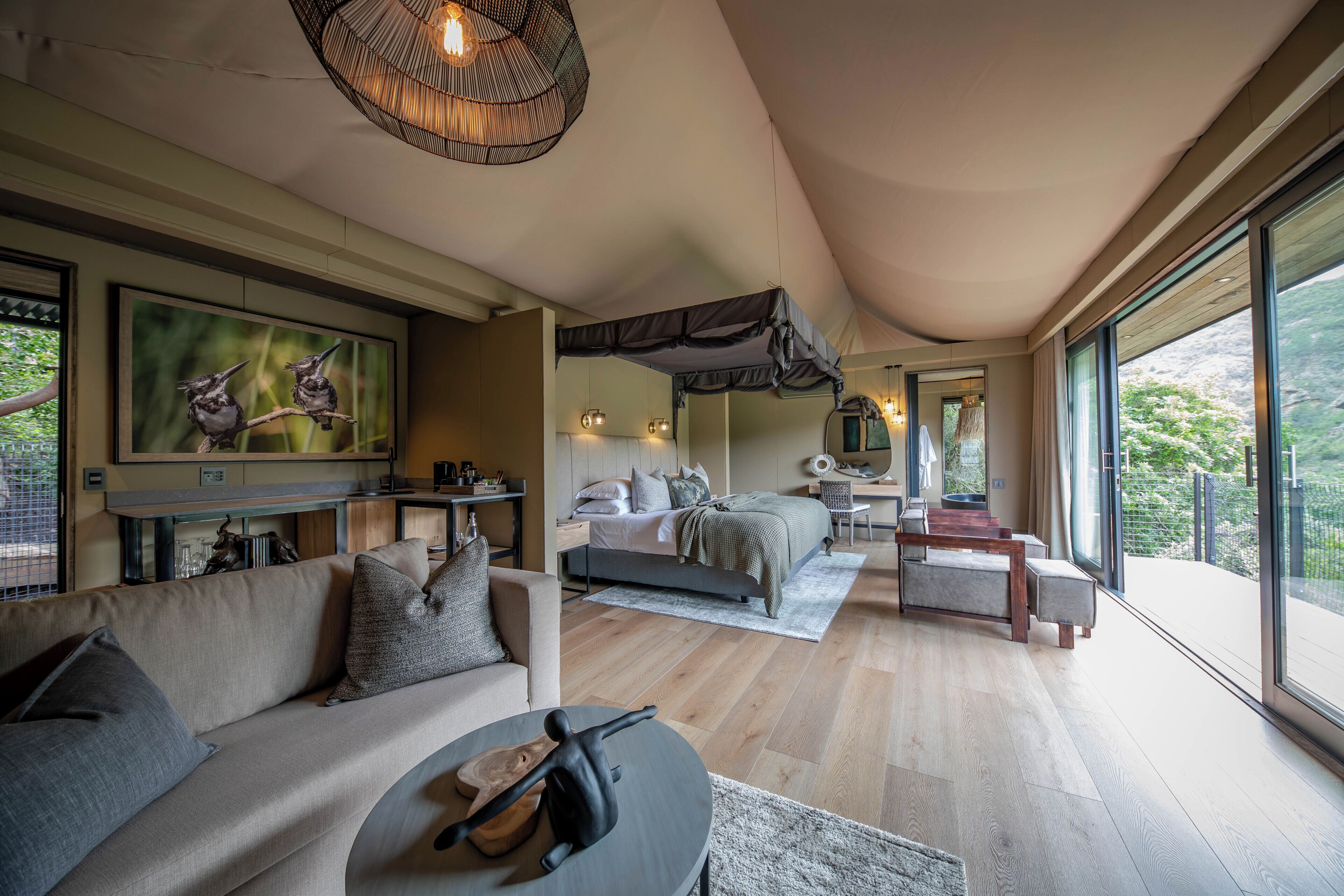 Une chambre moderne avec un grand lit, un canapé, une table à manger et une vue sur l’extérieur.