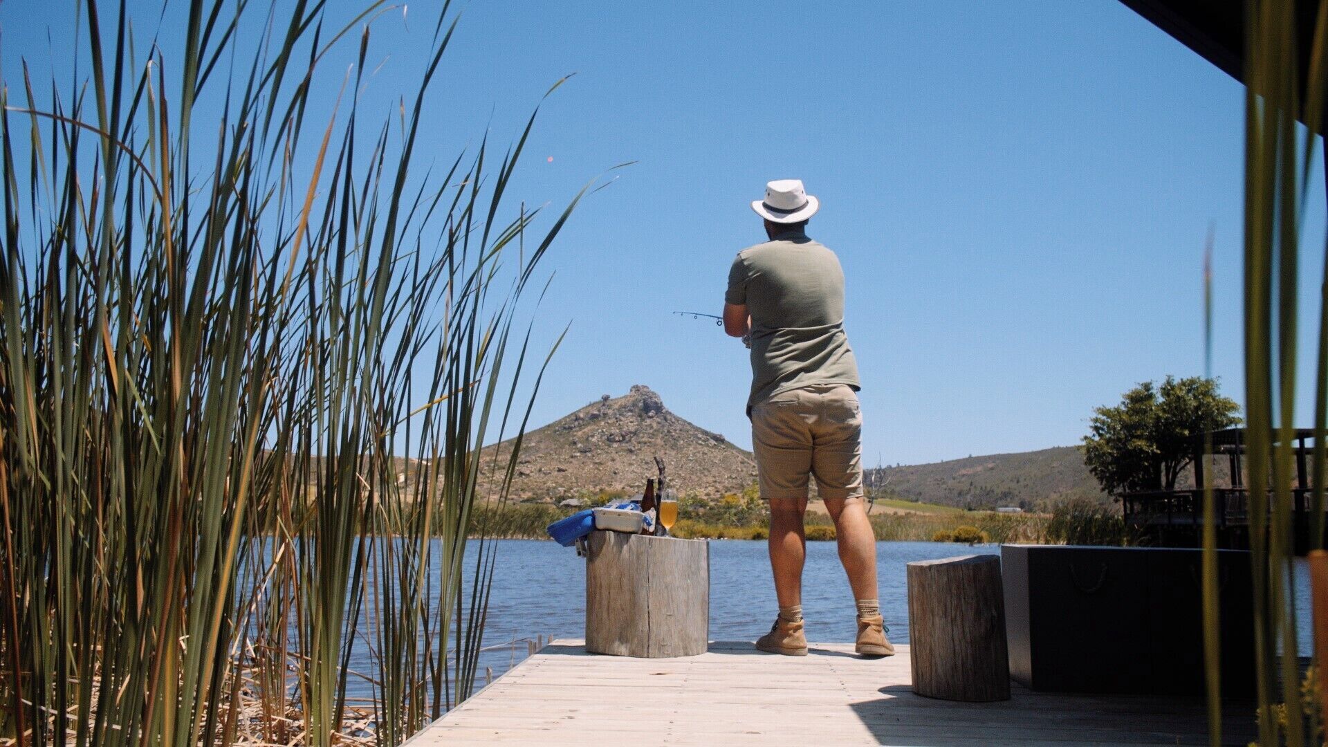 Una persona pescando en un muelle, con una montaña al fondo.