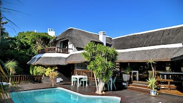 Alberca al aire libre, sombrillas en la alberca y camastros