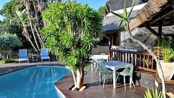 Alberca al aire libre, sombrillas en la alberca y camastros