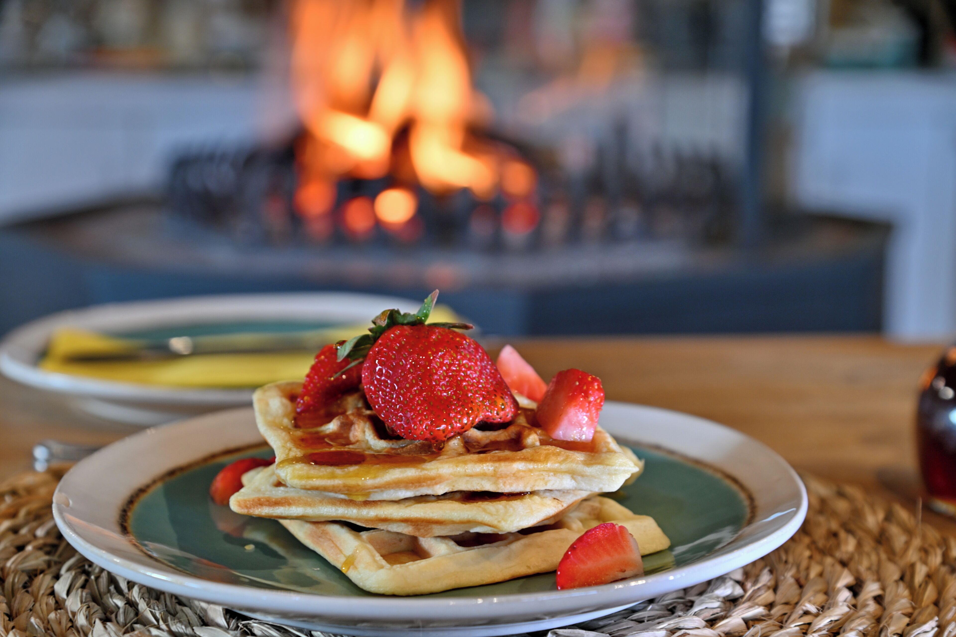A plate of waffles with strawberries on a woven placemat.