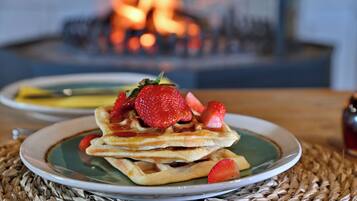 A plate of waffles with strawberries on a woven placemat.