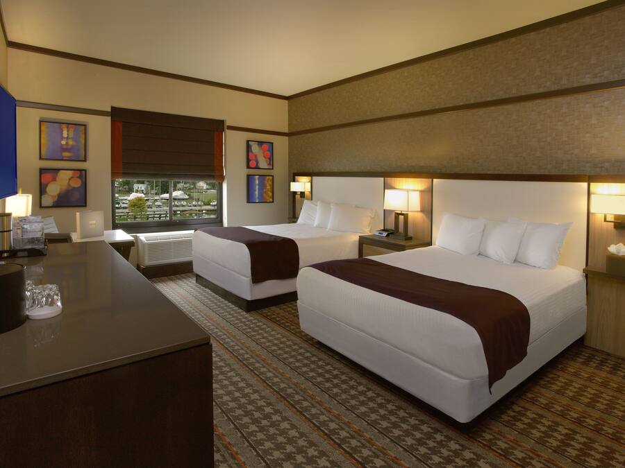 Habitación de hotel con dos camas, un escritorio y vistas al exterior.