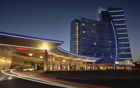 A modern hotel with a curved entrance and a tall, rectangular building in the background.