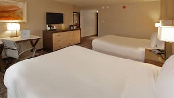 A hotel room with two beds, a desk, a chair, a TV, and a mirror.
