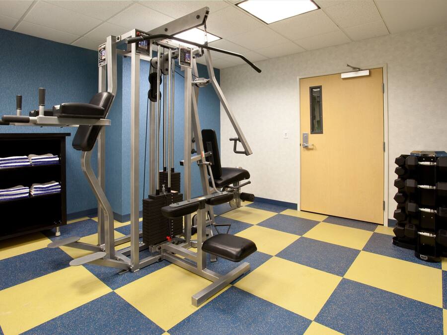 A gym with exercise equipment, a door, and a stack of dumbbells.