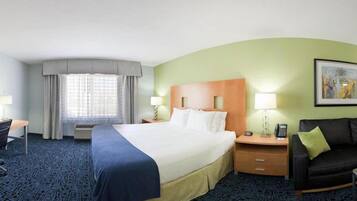 A hotel room with a large bed, a desk, a chair, a sofa, and a painting on the wall.