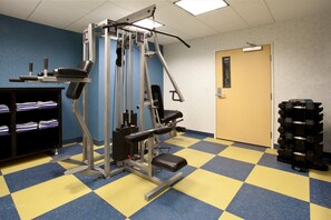 Ett gym med träningsutrustning, en dörr och en hög med hantlar.
