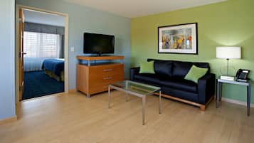 Una sala de estar moderna con televisor, sofá, mesa de centro y una obra de arte en la pared.