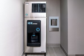A compact, stainless steel ice dispenser with a digital display and a water fountain.