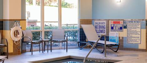 A pool area with a sign indicating no diving allowed. There are lounge chairs and a lifeguard chair.