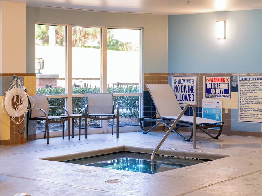 A pool area with a sign indicating no diving allowed. There are lounge chairs and a lifeguard chair.