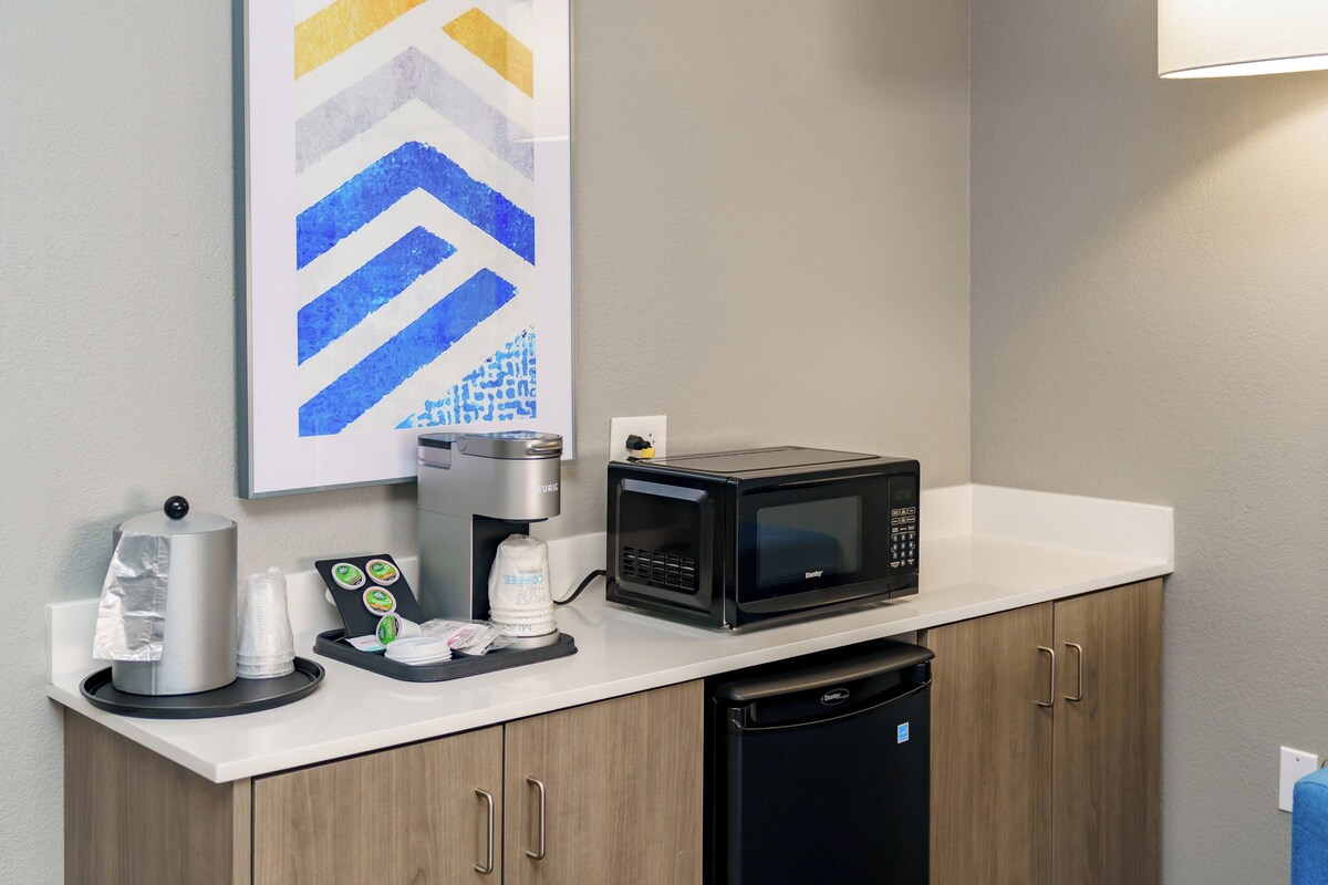 A kitchenette with a coffee maker, microwave, and dishwasher.