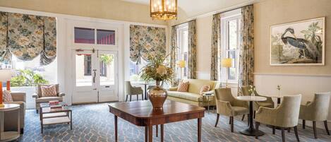 A spacious lobby with a patterned carpet, a wooden coffee table, a sofa, and several chairs.