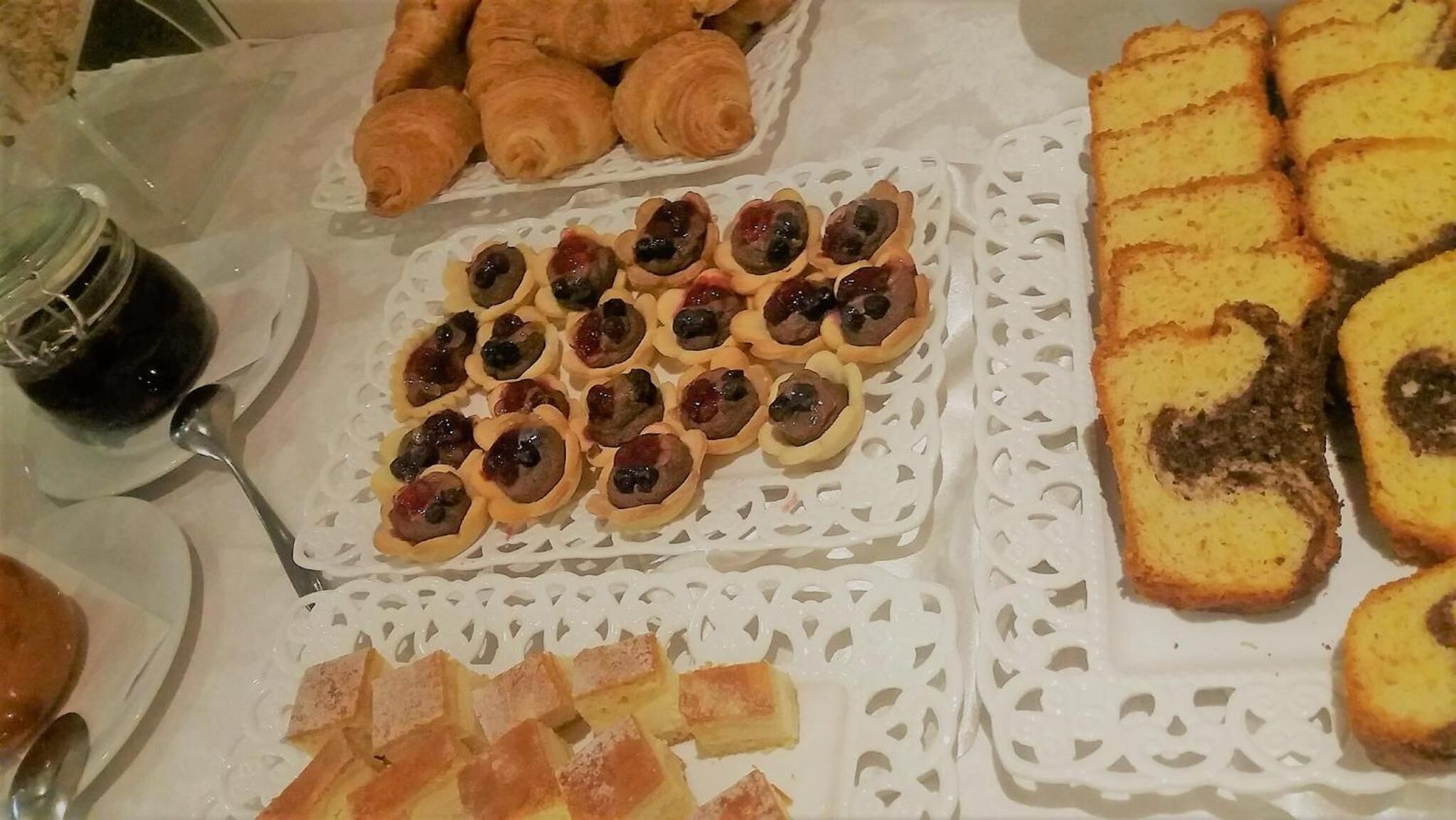A buffet with various food items including pastries, tarts, and bread.