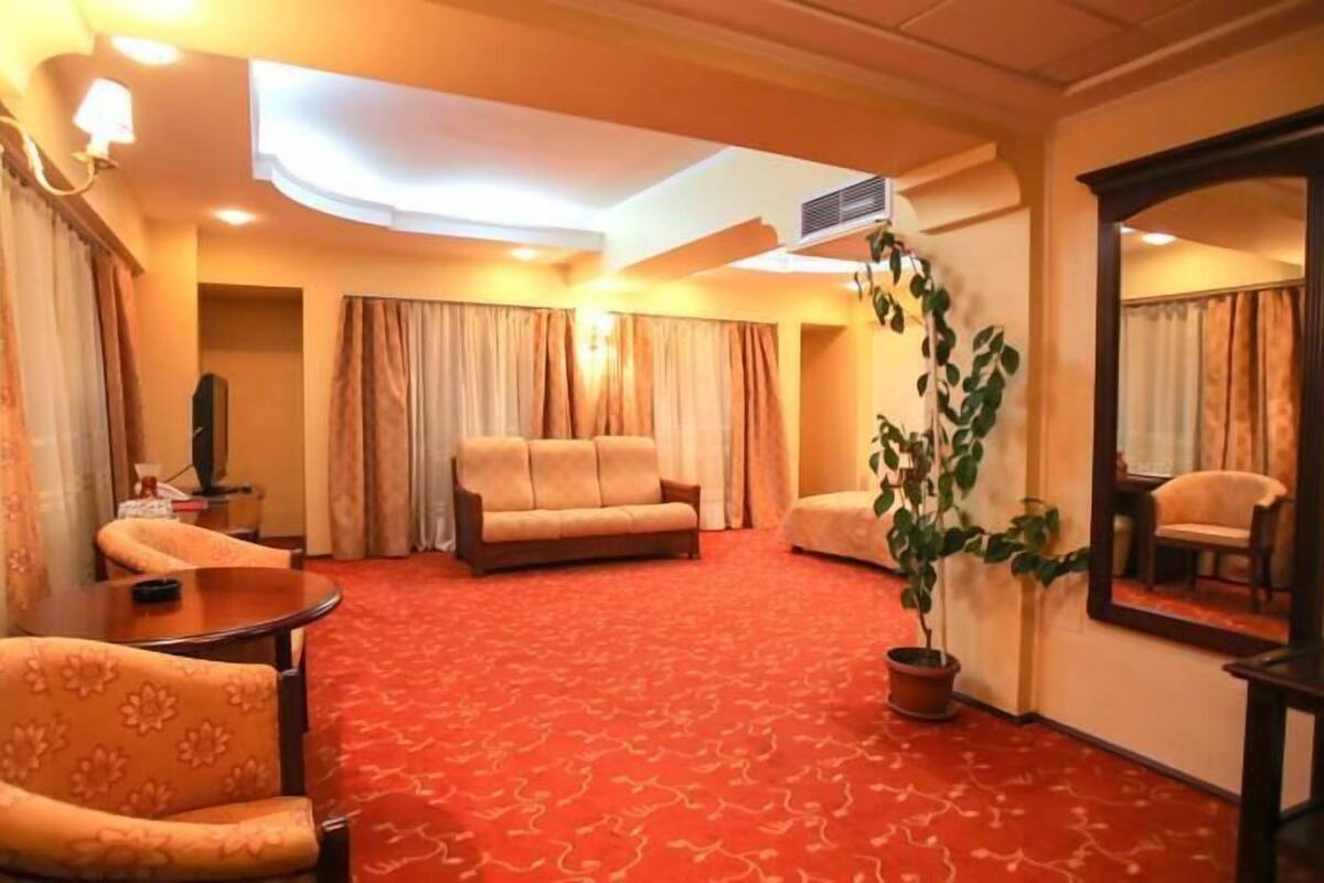 Hotellihuone, jossa on punainen matto, sohva, tuoli, pöytä ja peili.