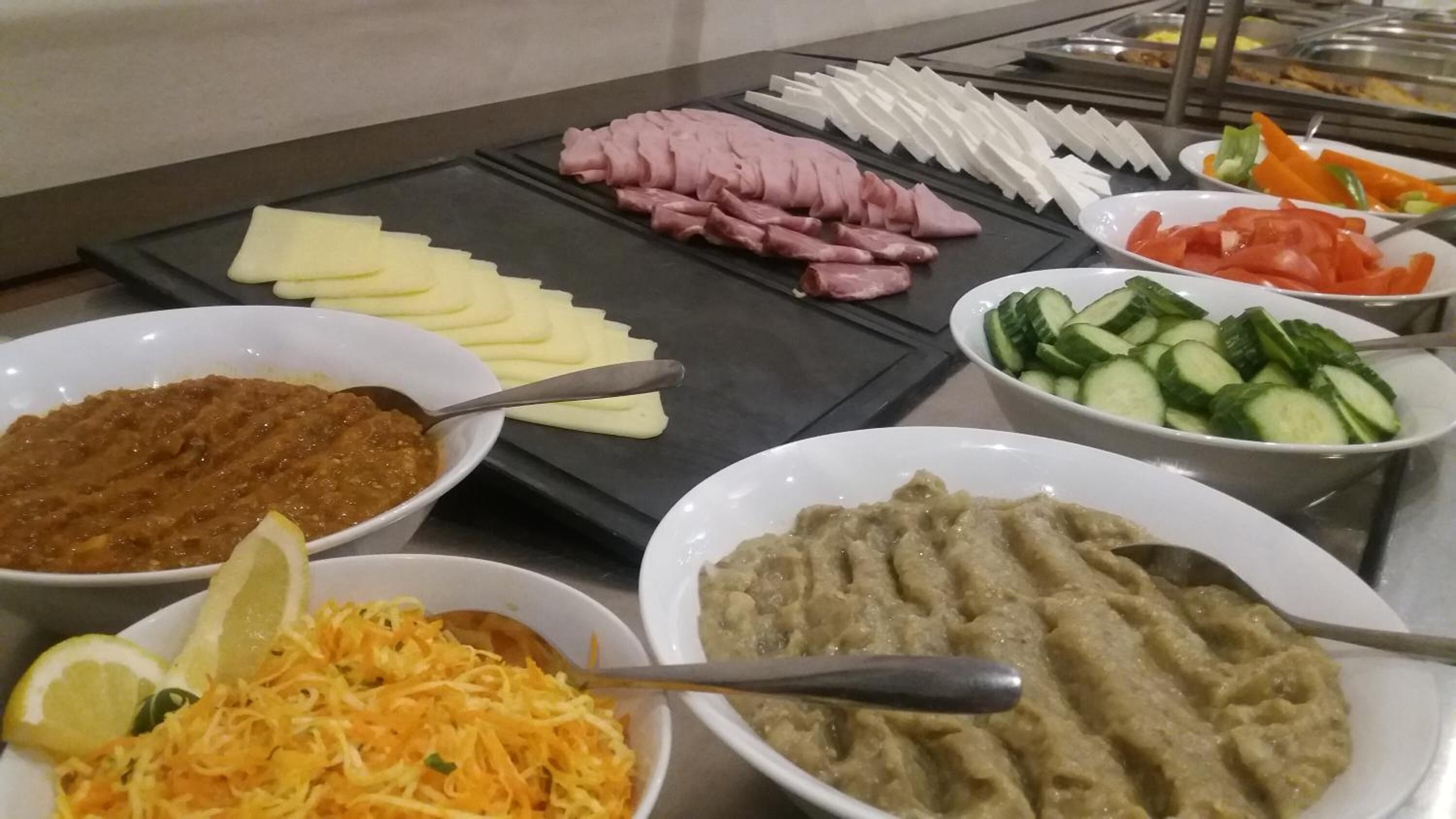 Un buffet proposant une variété de plats, notamment des viandes en tranches, des légumes et des sauces.