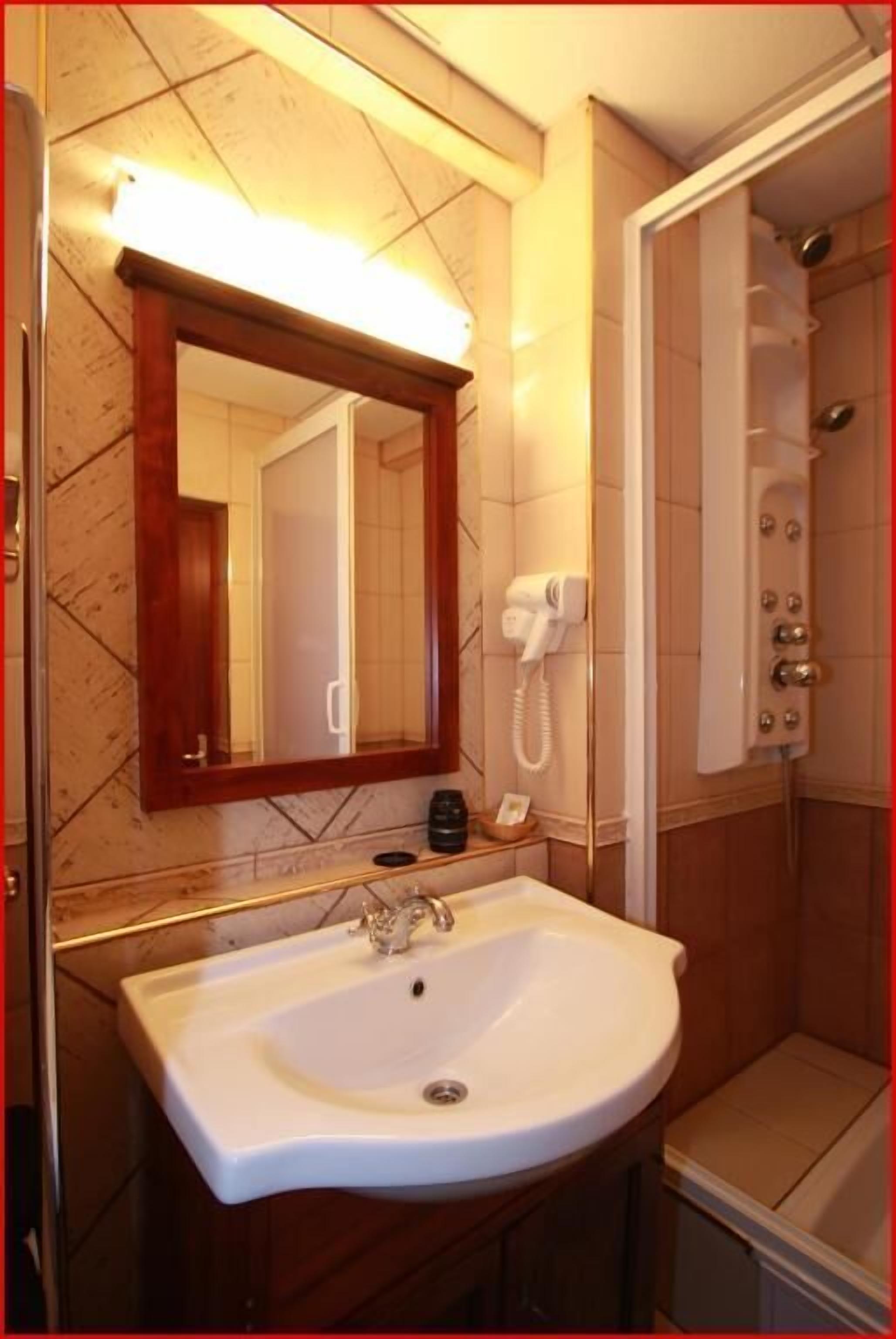 A bathroom with a sink, mirror, and shower.