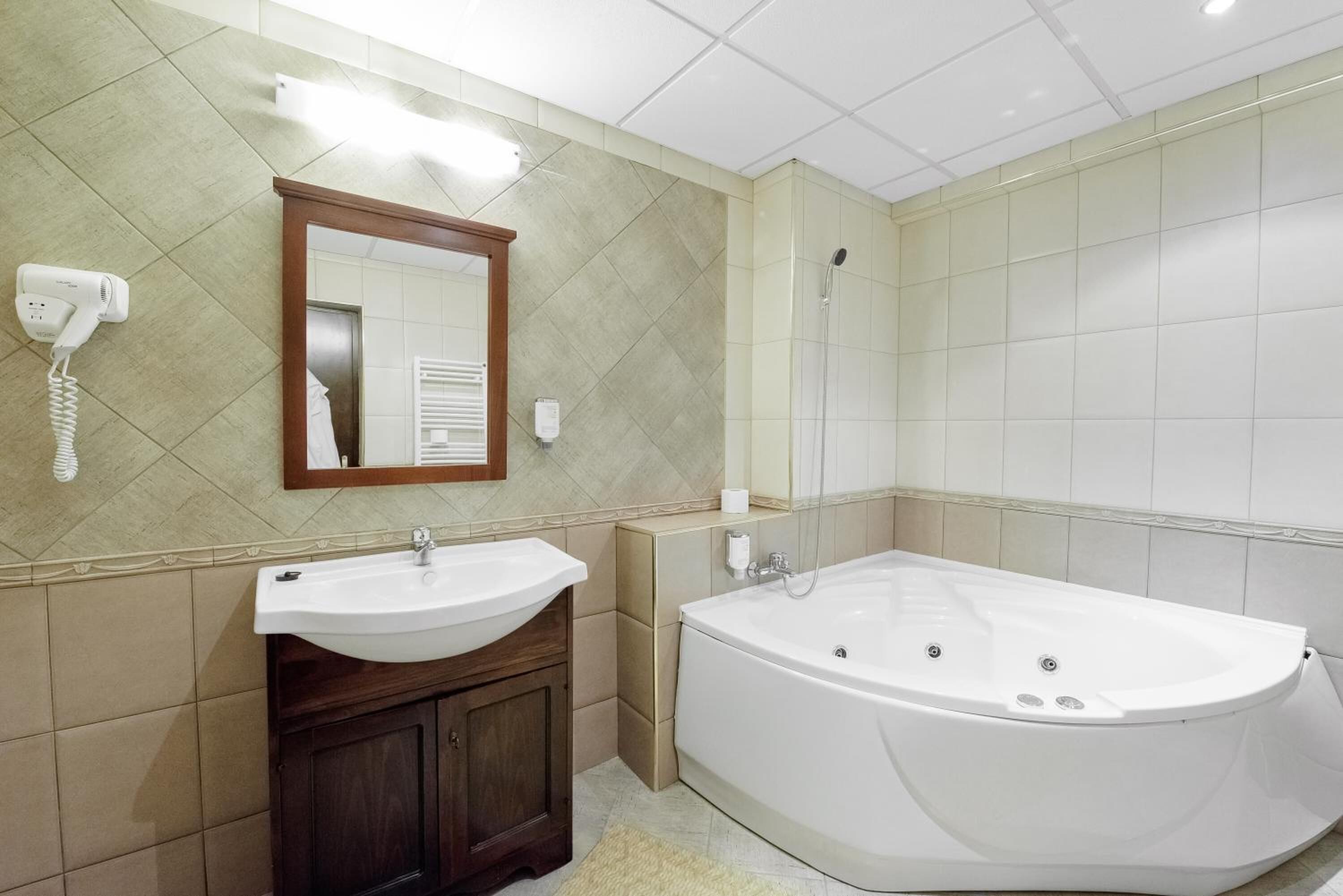 A bathroom with a sink, mirror, and bathtub.