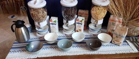 A kitchen counter with various food items and containers, including a coffee maker, bowls, and bags of oats and almond milk.