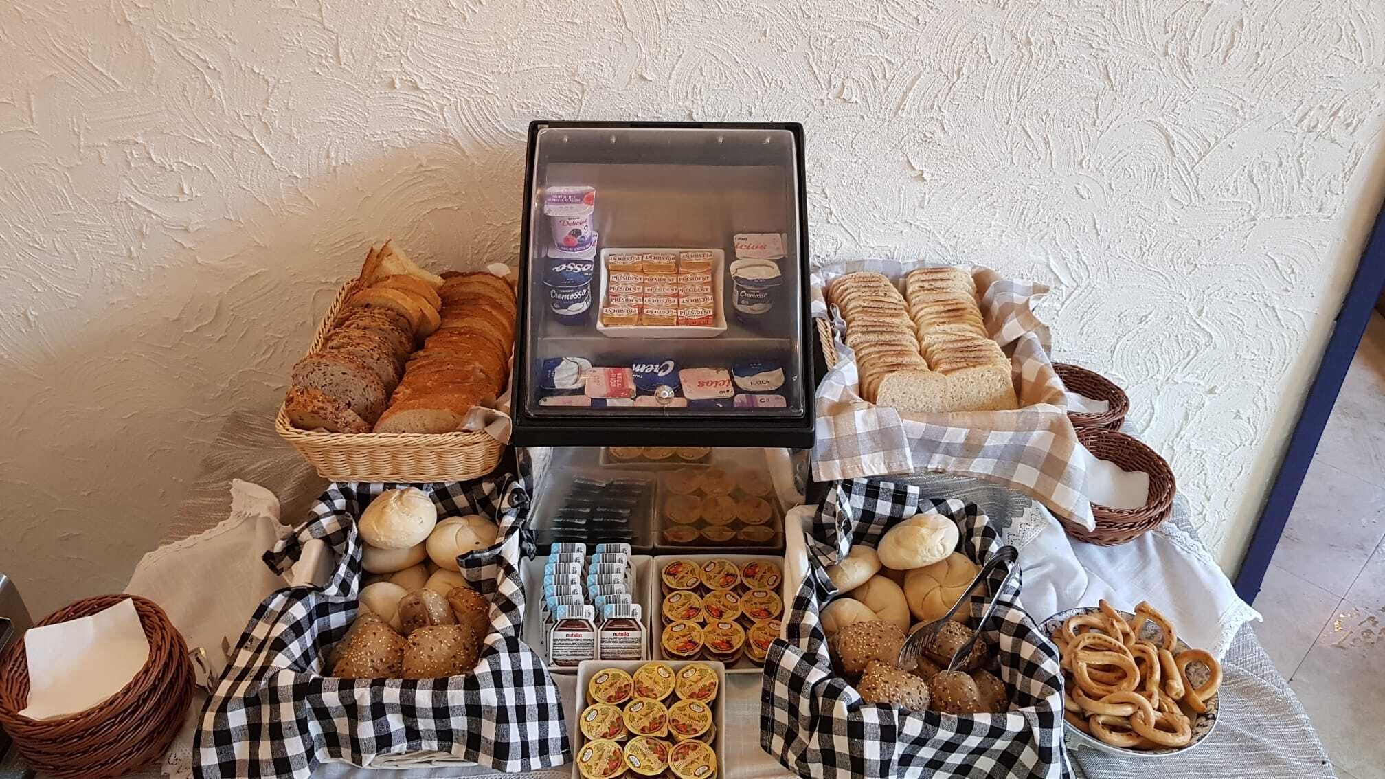 A display of various breads and pastries in baskets and trays, with a glass case in the center containing packaged goods.