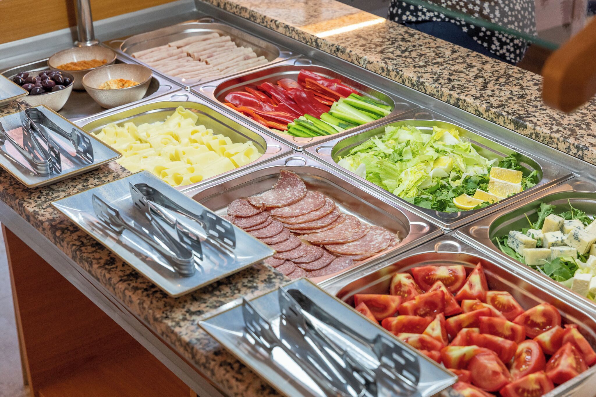 A buffet with various food items including meats, cheeses, and vegetables.