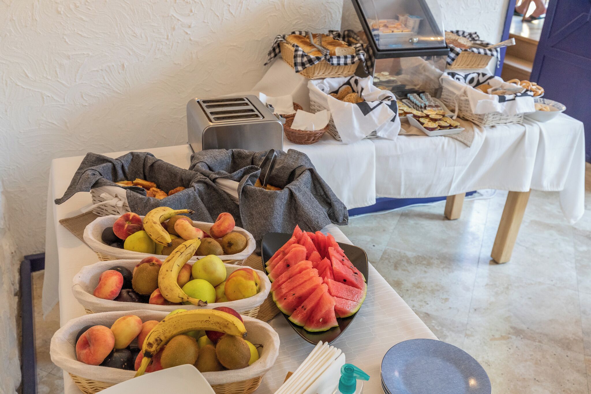 A buffet table with various fruits, bread, and pastries.