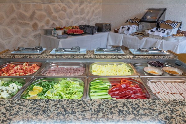 A buffet with various food options including meats, cheeses, and vegetables.