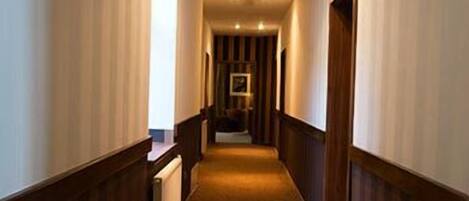 A hallway with wooden paneling on the walls and a carpeted floor.