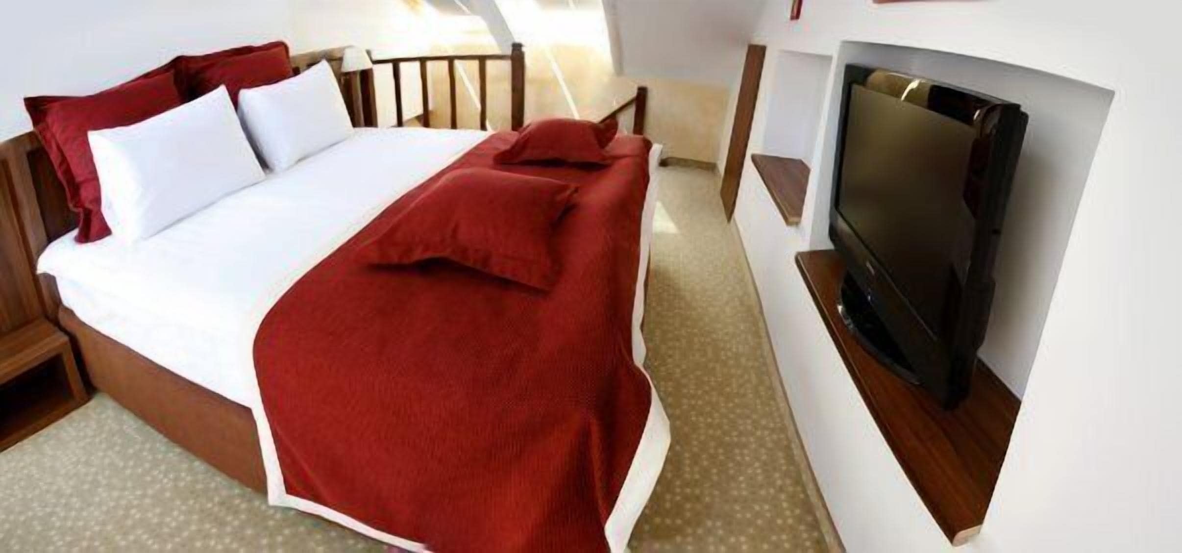 Een hotelkamer met een bed, een televisie en een houten hoofdeinde.