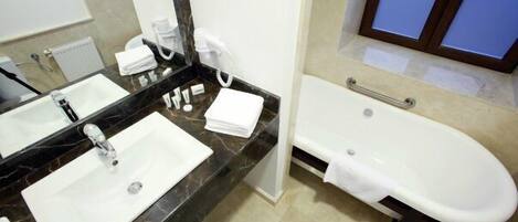 Un baño de hotel con lavamanos doble, un espejo grande, una bañera y un perchero para toallas.