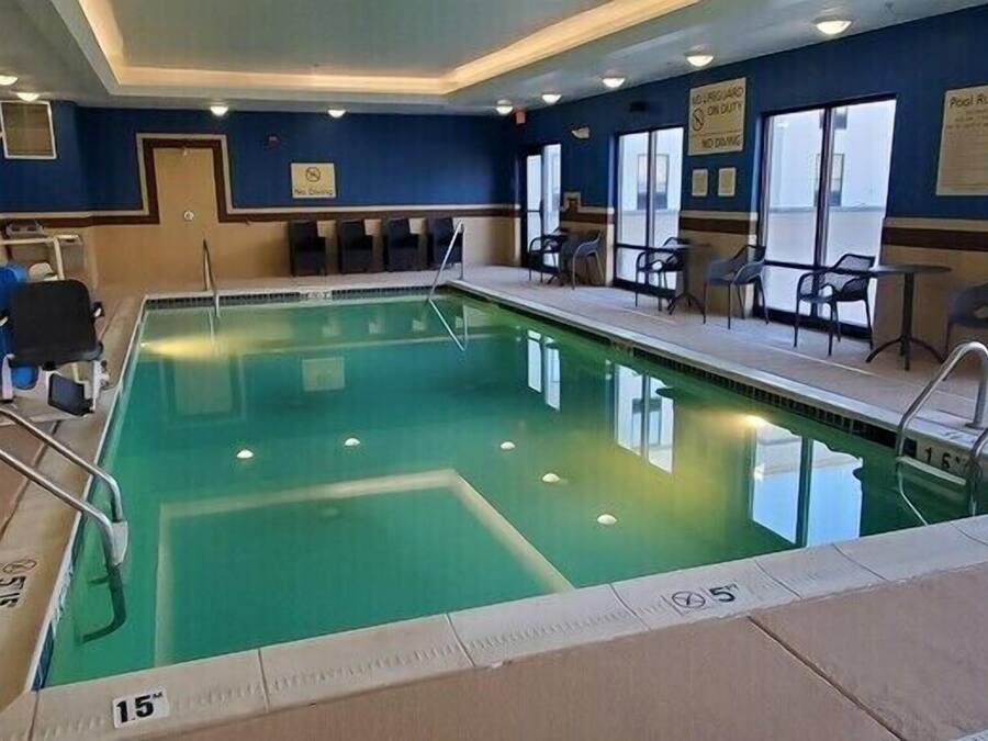 Ein Schwimmbecken mit deutlichen Bahnen, einem Rettungsschwimmerstuhl und einem Hinweisschild mit Poolregeln.