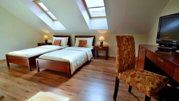 A bedroom with two beds, a TV, and a chair.