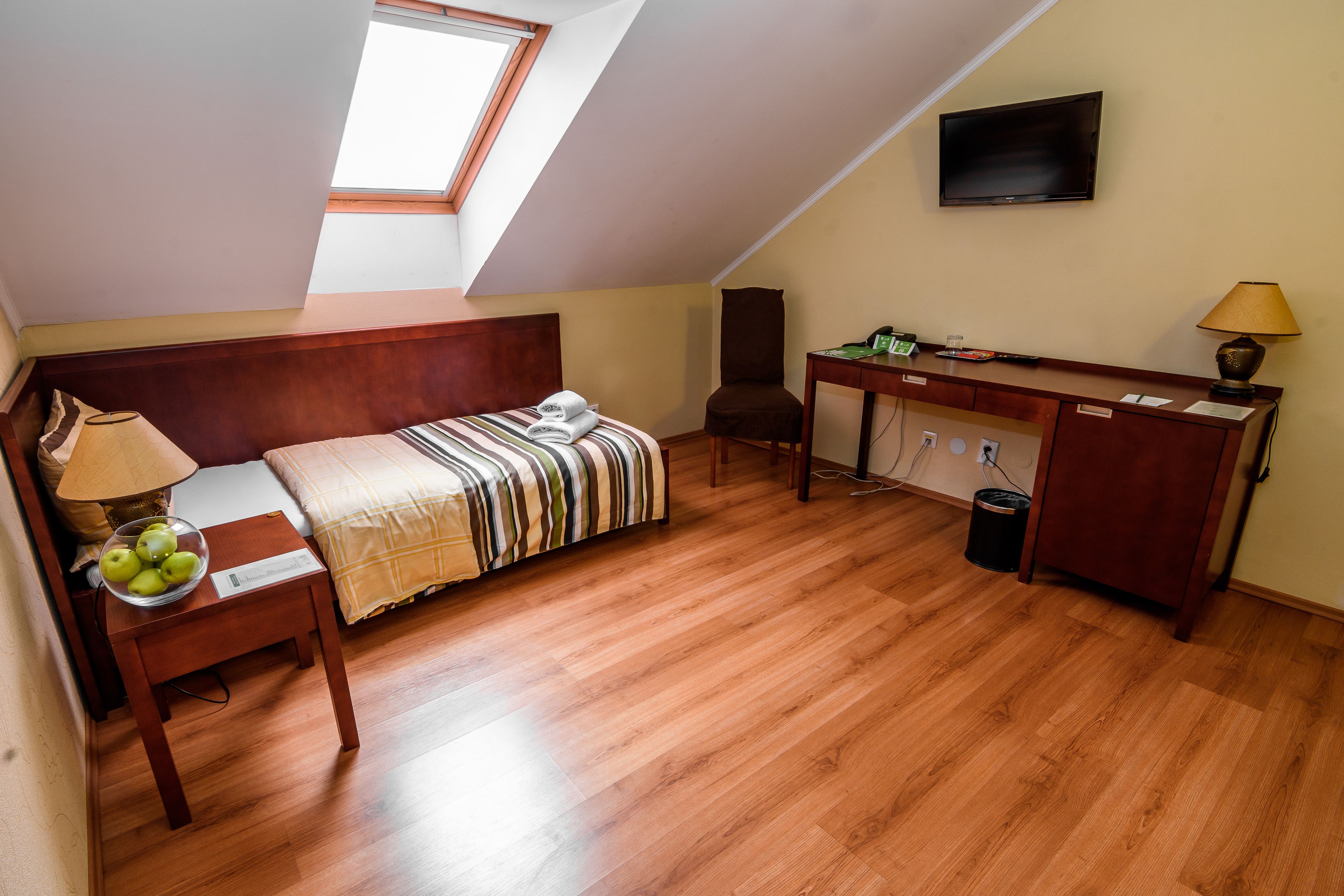 A room with a bed, a desk, a chair, a TV, and a window.