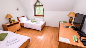Ein Zimmer mit zwei Betten, einem Schreibtisch mit Computer und einem Fenster mit Vorhängen.