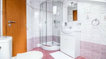 A bathroom with a glass-enclosed shower, a white sink, and a toilet.