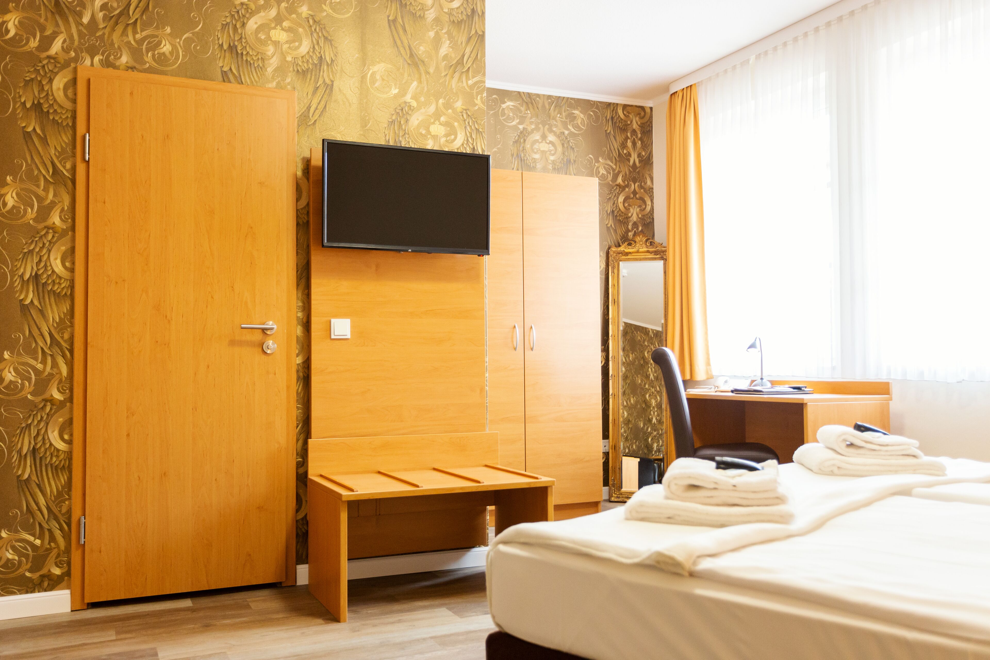 Une chambre d’hôtel comprenant un lit, un bureau, une chaise, une télévision et une armoire.