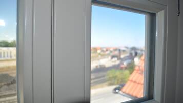 A window with a view of a building with a red roof and a clear blue sky.