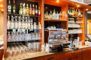Zona bar con scaffali di bottiglie di liquore e una macchina per caffè.