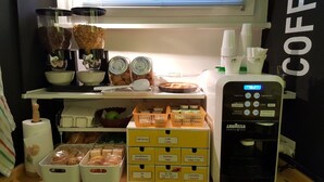 Una estación de café con una máquina de café, tazones y recipientes de café y azúcar.