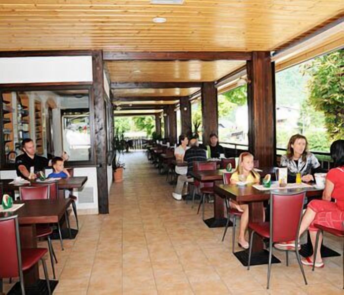 An indoor dining area with wooden ceiling beams, red chairs, and tables.