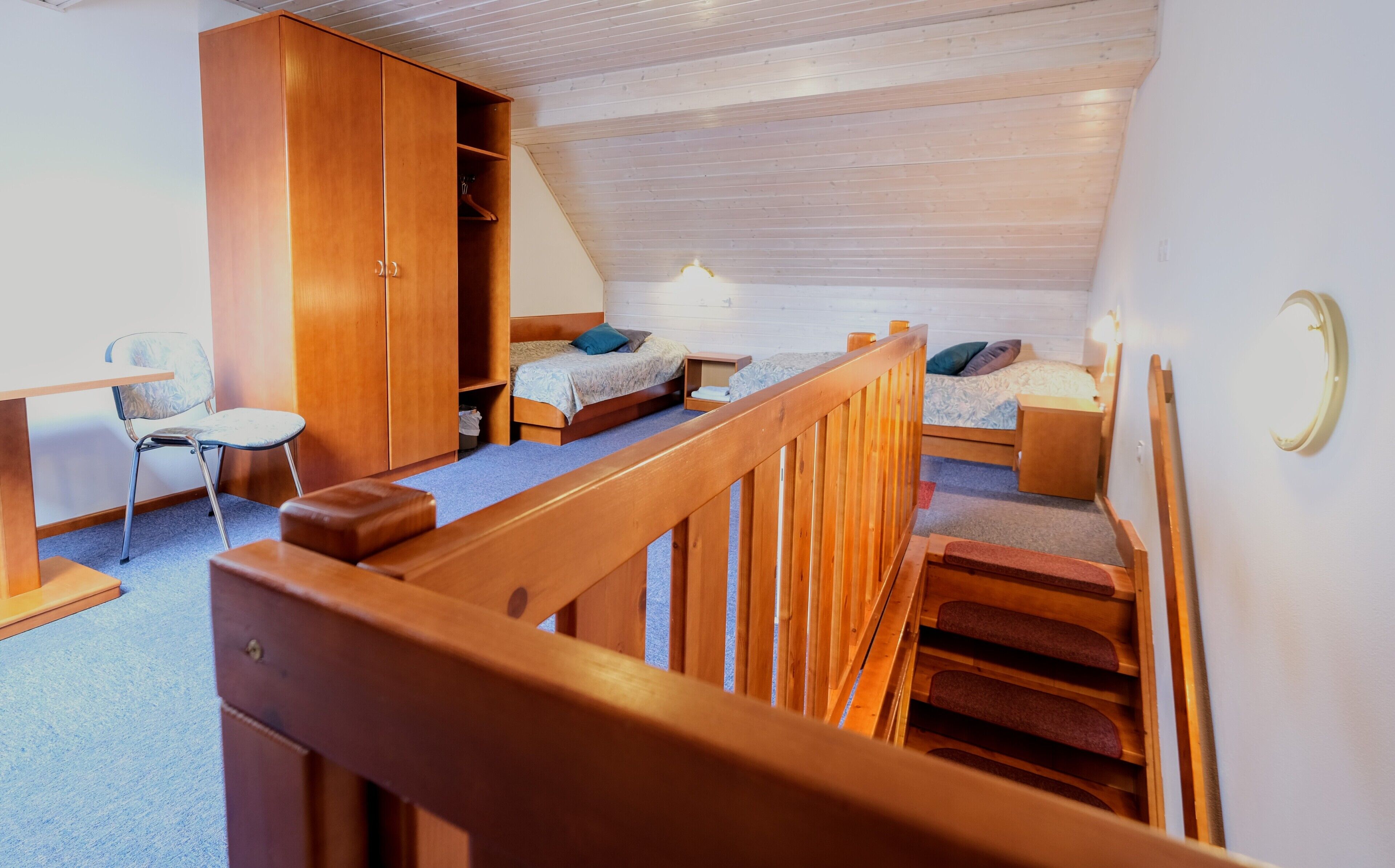 A dormitory room with two beds, a desk, a chair, and a wardrobe.