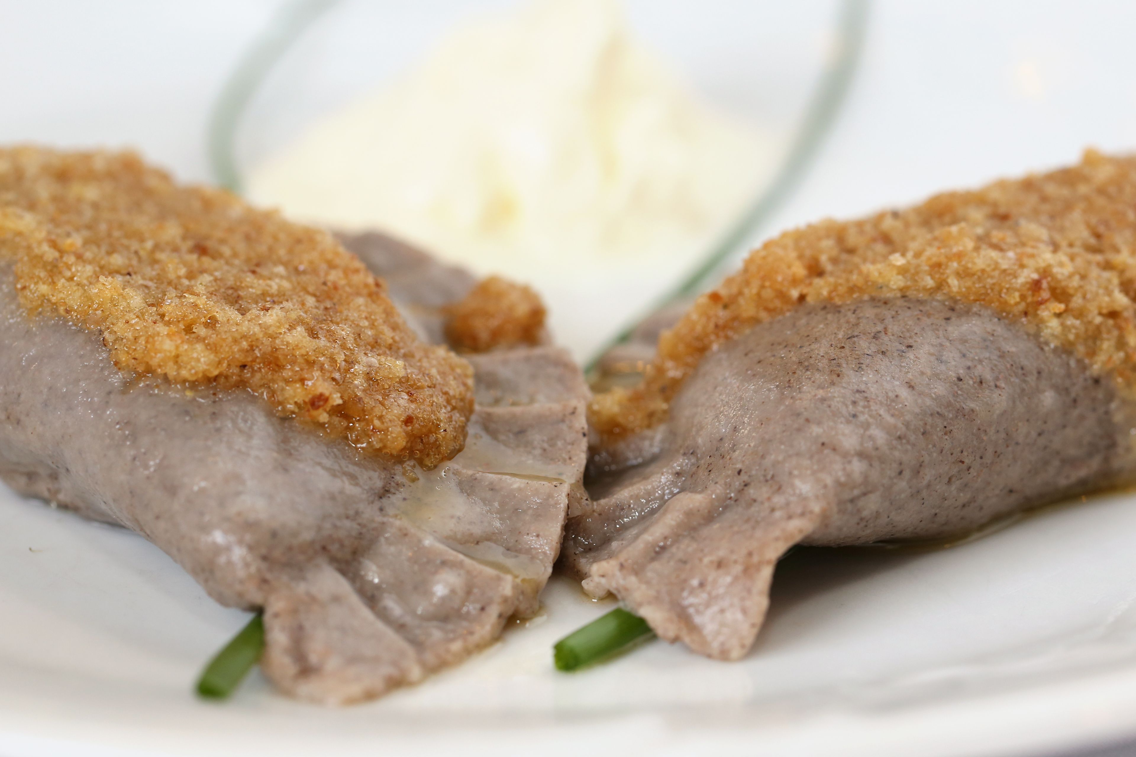 A plate with two pieces of breaded meat and a dollop of butter.