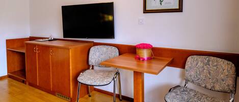 A room with a wooden desk, two chairs, a television, and a framed quote on the wall.