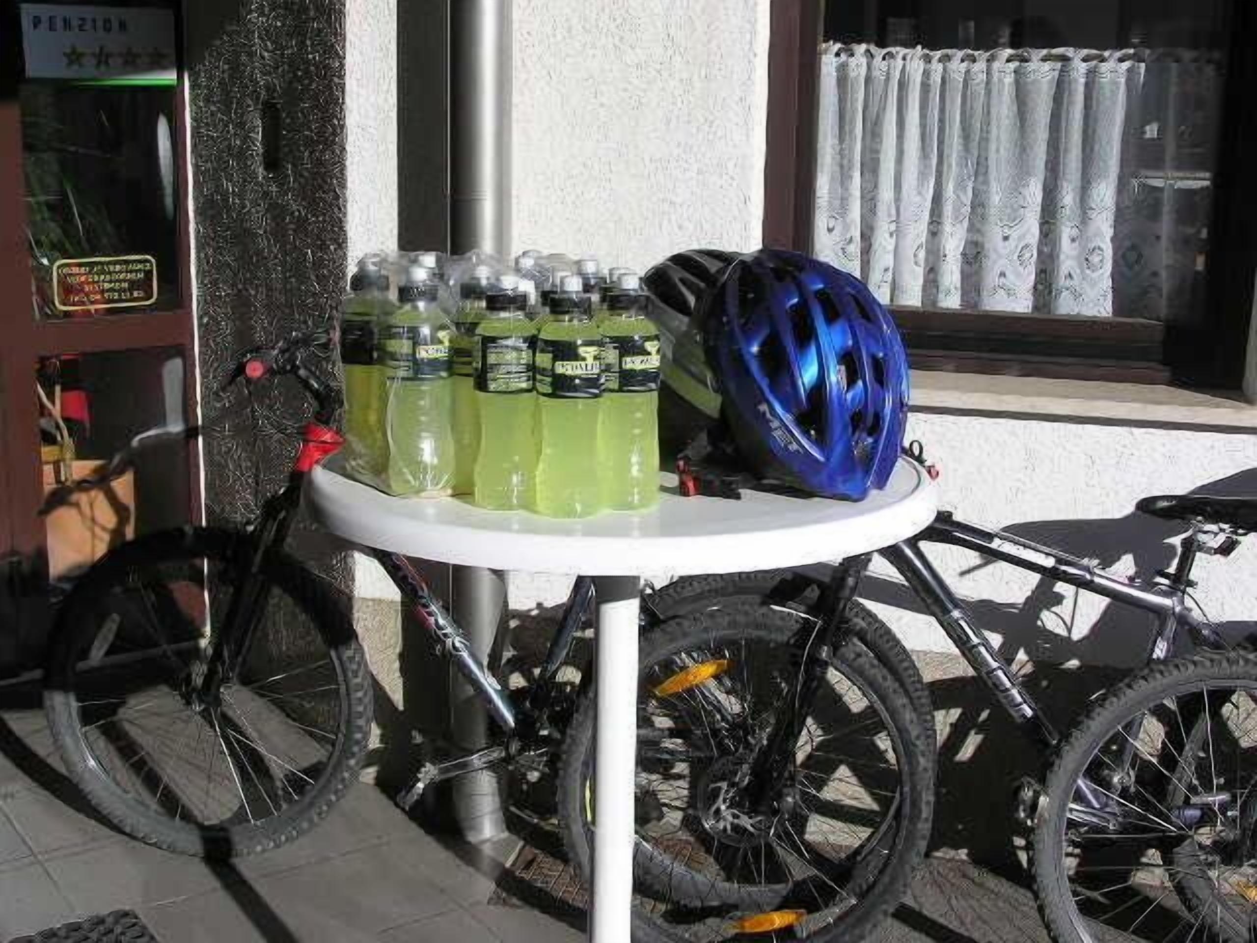 A bicycle parked next to a table with a blue helmet and bottles of sports drink.