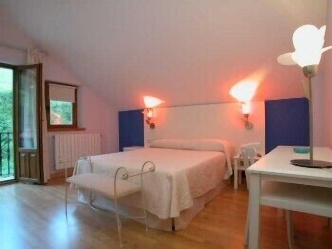 A bedroom with a bed, bedside tables, and a window.