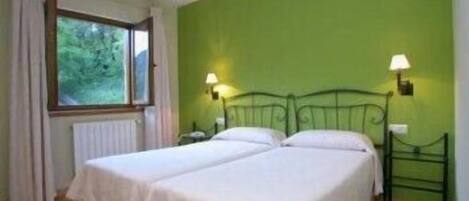 A room with two beds, a window with curtains, and two wall-mounted lamps.